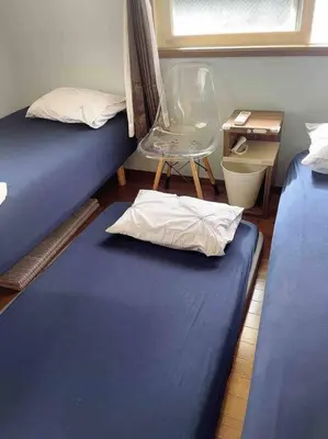 a room with two beds and a chair and a table at M&Ks house in Tokyo
