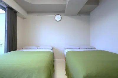 two beds in a room with a clock on the wall at Shinjuku Ryokan Retreat丶Local Tokyo Experience & Short Trips Hub丶walk to Higahsi Shinjuku station YEoL in Tokyo