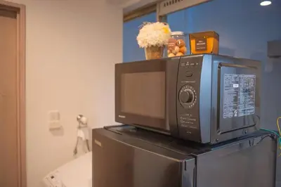 a microwave sitting on top of a refrigerator at \u94f6\u5ea7\u5408\u4e4b\u5c4b \u7b51\u5730\u5e02\u573a\u5730\u94c1\u4e09\u5206\u949f \u94f6\u5ea7\u5f92\u6b65\u5341\u5206\u949f in Tokyo
