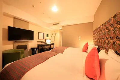 a bedroom with a bed with red pillows and a tv at Centurion Hotel Ikebukuro Station in Tokyo