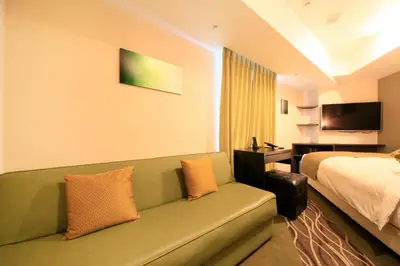 a hotel room with a couch and a bed at Centurion Hotel Ikebukuro Station in Tokyo
