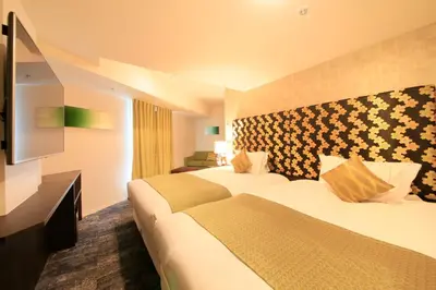 a hotel room with two beds and a flat screen tv at Centurion Hotel Ikebukuro Station in Tokyo