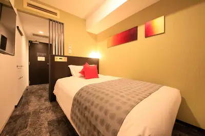 a bedroom with a bed with a red pillow at Centurion Hotel Ikebukuro Station in Tokyo