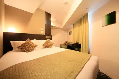 a hotel room with a bed with pillows and a desk at Centurion Hotel Ikebukuro Station in Tokyo