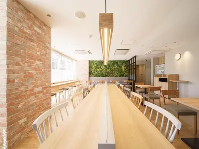 a dining room with tables and chairs and a brick wall at Super Hotel Shinagawa Aomono-Yokocho in Tokyo