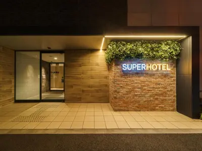 a sign for a super hotel on a brick wall at Super Hotel Shinagawa Aomono-Yokocho in Tokyo