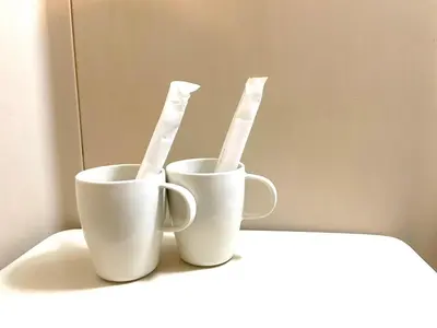 two white cups sitting on a counter with toothbrushes at Tokyo Stay Kitashinjyuku in Tokyo