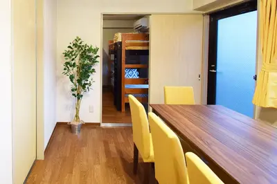 a dining room with a wooden table and yellow chairs at Hostel Inn Tokyo Ryogoku in Tokyo