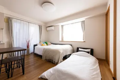 a room with two beds and a table and a window at ROMANTIC FLAT IN THE HEART OF SHIBUYA / 7MIN WALK in Tokyo