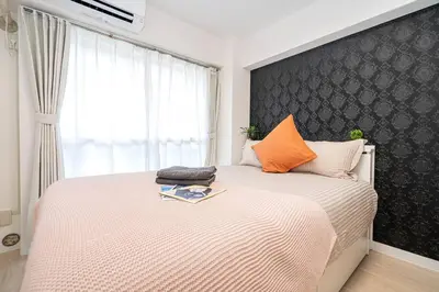 a bedroom with a large bed with an orange pillow at \u65b0\u5bbf\u533a\u5e02\u4e2d\u5fc3\u6b4c\u821e\u4f0e\u753a\u9996\u9009\u623f\u6e90\u514d\u8d39Wi-Fi\u3002 in Tokyo
