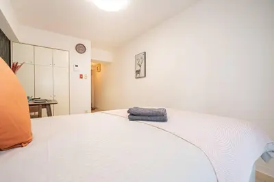 a white bed with a blue towel on it at \u65b0\u5bbf\u533a\u5e02\u4e2d\u5fc3\u6b4c\u821e\u4f0e\u753a\u9996\u9009\u623f\u6e90\u514d\u8d39Wi-Fi\u3002 in Tokyo