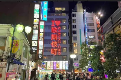 a busy city street at night with neon signs at \u65b0\u5bbf\u533a\u5e02\u4e2d\u5fc3\u6b4c\u821e\u4f0e\u753a\u9996\u9009\u623f\u6e90\u514d\u8d39Wi-Fi\u3002 in Tokyo