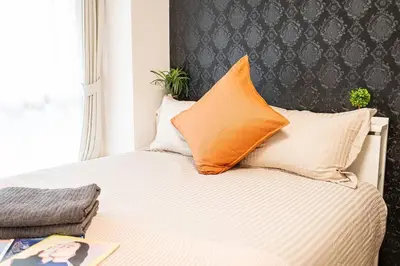 a bed with an orange pillow on top of it at \u65b0\u5bbf\u533a\u5e02\u4e2d\u5fc3\u6b4c\u821e\u4f0e\u753a\u9996\u9009\u623f\u6e90\u514d\u8d39Wi-Fi\u3002 in Tokyo