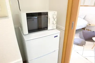 a microwave sitting on top of a refrigerator at \u5922\u306e\u820e \u6d45\u8349 Yumenoya Asakusa in Tokyo