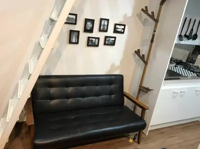 a black leather bench sitting under a stair case at Shinagawa New Apt Easy access to both Haneda & Narita Airport in Tokyo