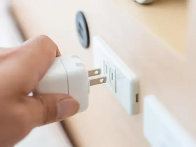 a person holding a white electrical outlet with a clock on a wall at Super Hotel Asakusa in Tokyo