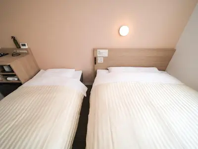 two twin beds in a room with a desk at Super Hotel Asakusa in Tokyo