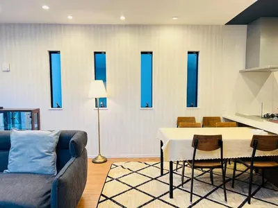 a living room with a table and a kitchen with blue windows at Zaki-House-EG0307 in Tokyo