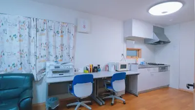 a kitchen with a table and two blue chairs at \u6771\u8cc0\u65c5\u9928 in Tokyo