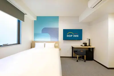 a bedroom with a bed and a desk and a sign at Hop Inn Tokyo Asakusa in Tokyo