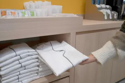 a person holding a stack of towels in a closet at Hop Inn Tokyo Asakusa in Tokyo