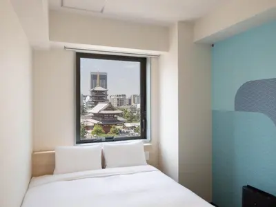 a bedroom with a window with a view of a city at Hop Inn Tokyo Asakusa in Tokyo