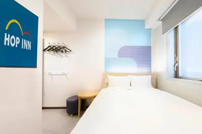a bedroom with a bed and a sign that says hop inn at Hop Inn Tokyo Asakusa in Tokyo