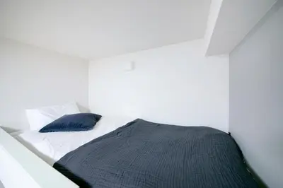 a white bedroom with a bed with a blue pillow at \u30ea\u30a2\u30eb\u9326\u7cf8101 in Tokyo