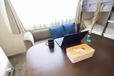 a laptop computer sitting on a table in a living room at “1ST ROOM” 内装デザイナー監修！30㎡ 最大6名 経堂駅から徒歩5分 築浅 良質な暮らしを in Tokyo