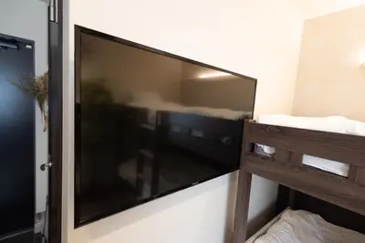 a large flat screen television hanging on a wall at “1ST ROOM” 内装デザイナー監修！30㎡ 最大6名 経堂駅から徒歩5分 築浅 良質な暮らしを in Tokyo