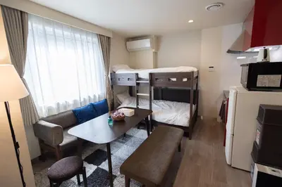 a small room with two bunk beds and a table at “1ST ROOM” 内装デザイナー監修！30㎡ 最大6名 経堂駅から徒歩5分 築浅 良質な暮らしを in Tokyo