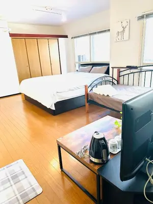 a room with two beds and a desk with a computer at \u5e73\u548c\u5c9b\u6c11\u5bbf in Tokyo