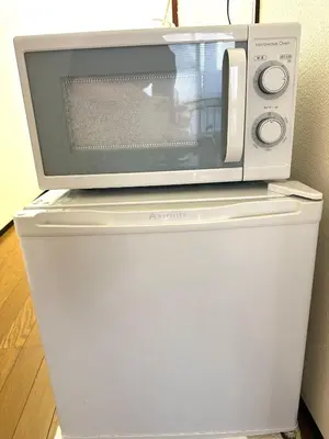 a microwave sitting on top of a refrigerator at \u5e73\u548c\u5c9b\u6c11\u5bbf in Tokyo