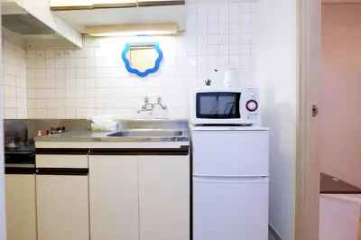 a kitchen with a microwave on top of a refrigerator at \u5922\u306e\u820e \u65b0\u5bbf Yumenoya Shinjuku in Tokyo