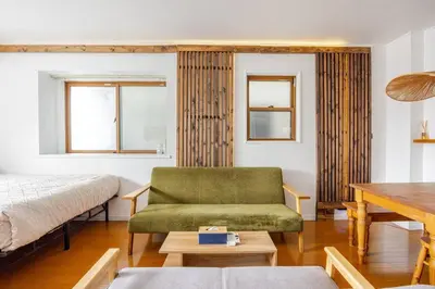 a living room with a green couch and a bed at \u6771\u4eac\u99c5\u307e\u30677\u5206 \u65b0\u5c0f\u5ca980\u5e73\u7c73\u8d85\u306e\u5e83\u3005\u30cf\u30a6\u30b9\u3010\u6210\u7530\u7a7a\u6e2f1\u6642\u9593,\u79cb\u8449\u539f,\u65b0\u5bbf,\u6d45\u8349\u30a2\u30af\u30bb\u30b9\u3011\u56e3\u4f53\u65c5\u884c in Tokyo
