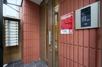 a red tiled wall with a door and a sign at Shinjuku colorbee pretty house103 in Tokyo