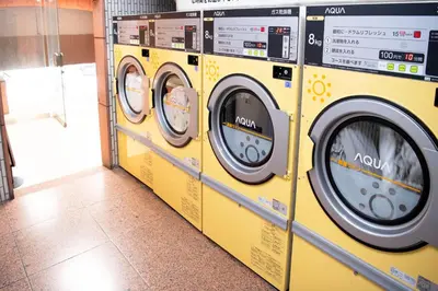 a row of yellow washing machines in a laundrette at Shinjuku central apartment! 3stops to Shibuya station 3mins walk to station in Tokyo