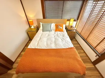 a bedroom with a large bed with an orange blanket at TOKYO HOSHI VILLIA-Private Villa in Tokyo ideal for groups and families in Tokyo