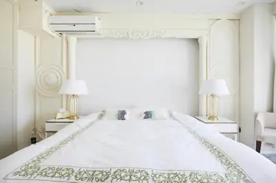 a white bedroom with a large white bed with two lamps at Reimi Mondo501 in Tokyo