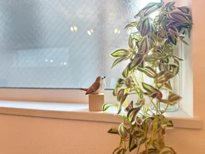 a bird sitting on a window sill next to a plant at nestay villa tokyo sugamo in Tokyo