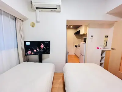 two beds in a room with a tv on the wall at JUN Kabukicho-SJ0096 in Tokyo