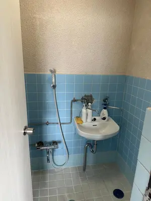 a blue tiled bathroom with a sink and a shower at QQ Umeyashiki in Tokyo