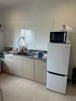 a kitchen with a microwave on top of a refrigerator at QQ Umeyashiki in Tokyo