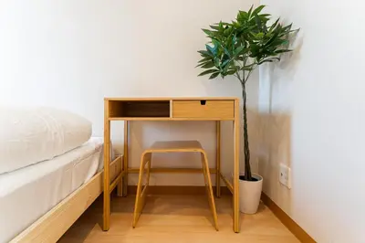 a desk with a chair next to a bed and a potted plant at E JOY INN-East Nipoori Branch in Tokyo
