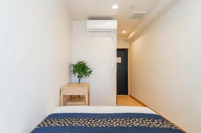 a bedroom with a bed and a plant in it at E JOY INN-East Nipoori Branch in Tokyo