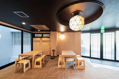 a room with tables and benches and windows at E JOY INN-East Nipoori Branch in Tokyo