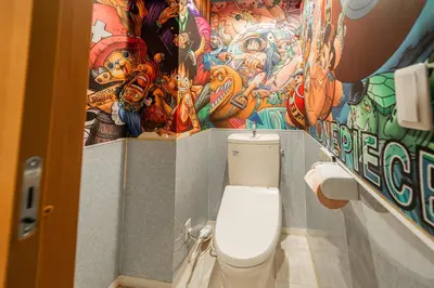 a bathroom with a toilet with a mural on the wall at E JOY INN-East Nipoori Branch in Tokyo
