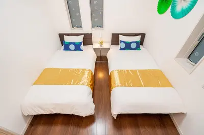 two beds in a room with white walls and wood floors at KYARA Hotel \u6d45\u8349 in Tokyo