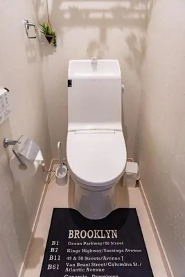 a bathroom with a white toilet with a sign on the floor at KYARA Hotel \u6d45\u8349 in Tokyo