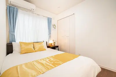 a bedroom with a bed with yellow pillows and a window at KYARA Hotel \u6d45\u8349 in Tokyo